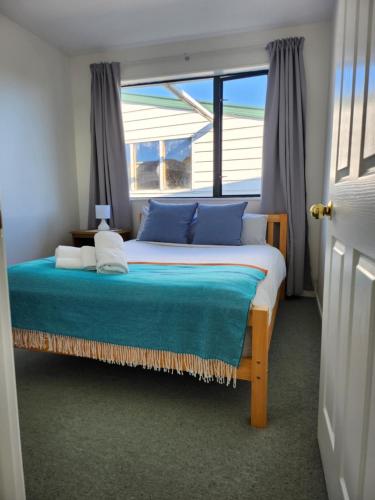 a bedroom with a bed with blue pillows and a window at Mountainview in Kaikoura