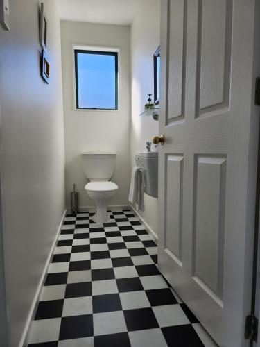 uma casa de banho com um WC e um piso xadrez preto e branco em Mountainview em Kaikoura