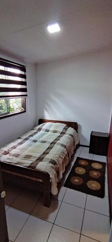 um quarto com uma cama num quarto com uma janela em Depto interior independiente em Temuco