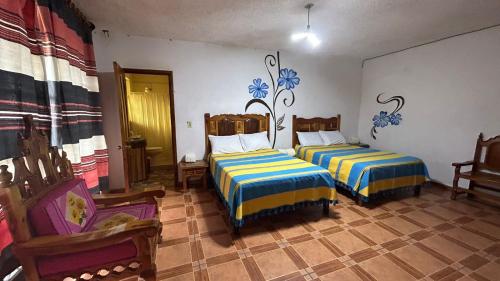 a room with two beds in a room with chairs at Hotel Colonial Taxco in Taxco de Alarcón