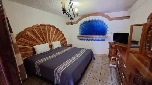 a bedroom with a bed and a dresser and a television at Hotel Colonial Taxco in Taxco de Alarcón