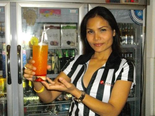 una mujer sosteniendo una bebida delante de un refrigerador en I Rovers en Pattaya centro