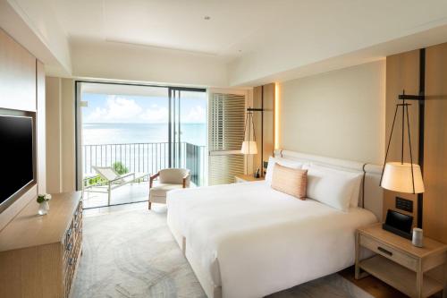 a hotel room with a bed and a large window at Halekulani Okinawa in Onna