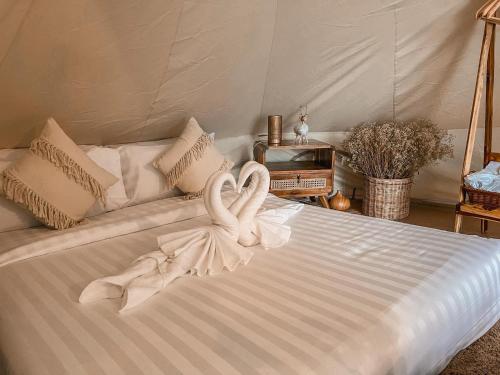 Una cama blanca con dos toallas de cisne. en Greenheart garden View Camp phuket, en Kata Beach
