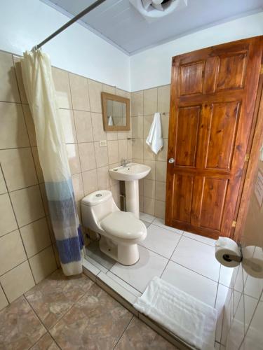 baño con aseo y lavabo y puerta de madera en Cabinas Nuestra Kasa, en Monteverde