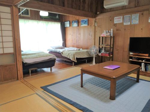 Cottage Yakusugi House في ياكوشيما: غرفة معيشة مع سرير وطاولة في غرفة