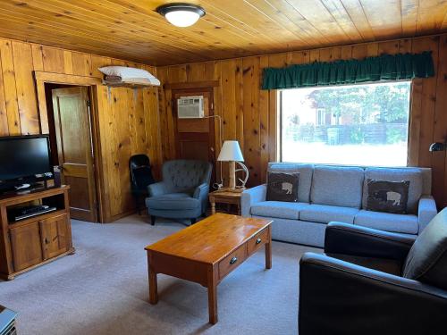 a living room with a couch and a table and a tv at Faithful Street Inn in West Yellowstone
