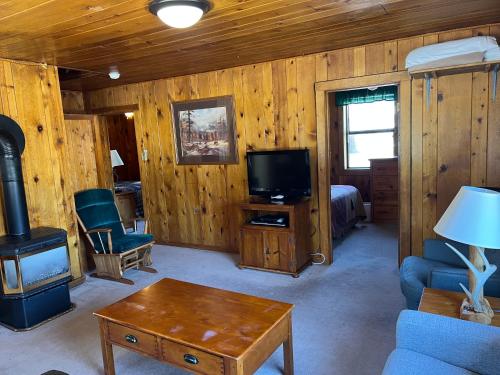 a living room with a room with a fireplace and a tv at Faithful Street Inn in West Yellowstone