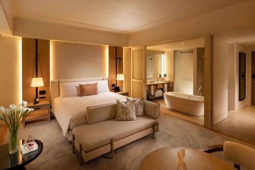 a hotel room with a bed and a bath tub at Halekulani Okinawa in Onna
