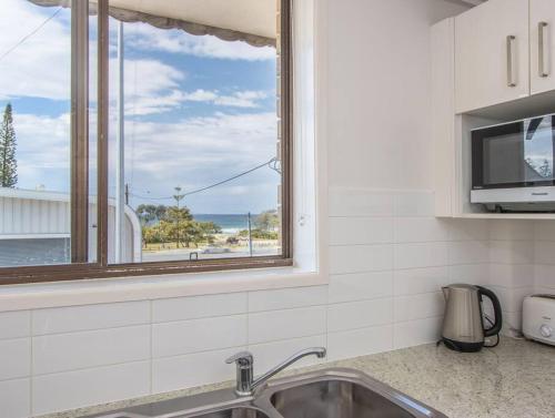 a kitchen with a sink and a window at Kingscliff Beachfront Abode - Hosted by Holiday Management in Kingscliff