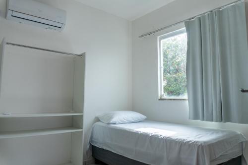 ein weißes Schlafzimmer mit einem Bett und einem Fenster in der Unterkunft Casa Estrela do Mar - Aluguel por Temporada Barra de São Miguel in Barra de São Miguel
