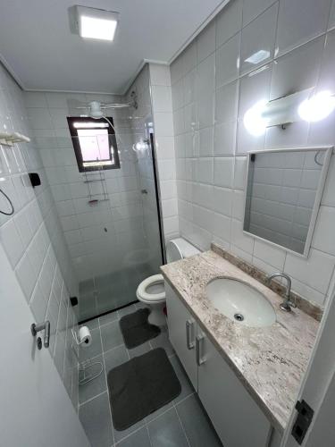 a bathroom with a sink and a toilet and a mirror at Guarujá enseada, apto a 150m da praia. in Guarujá