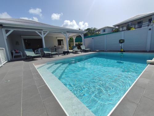 Una gran piscina azul con sillas y una casa. en Ti kaz an NOU **, en Sainte-Rose