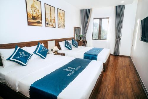 2 camas en una habitación de hotel con almohadas azules y blancas en Milan Hotel Ninh Bình en Ninh Binh