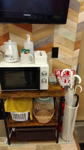 a microwave oven on a shelf with some dishes at Hotel Jungle fun fun in Osaka