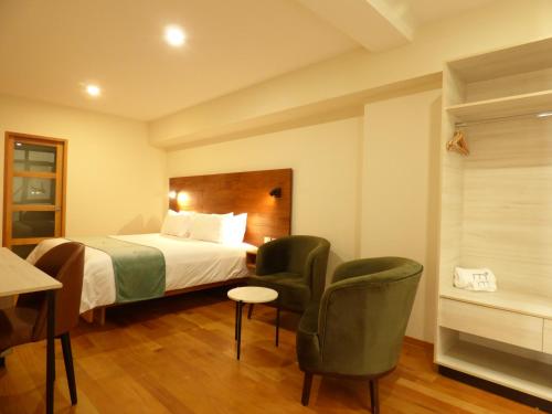 um quarto de hotel com uma cama e duas cadeiras em Muña Hotel em Talavera