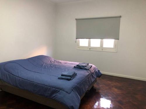 een slaapkamer met een bed met een blauw dekbed en een raam bij Patio! Parrilla! Cochera! 2 habitaciones in Godoy Cruz