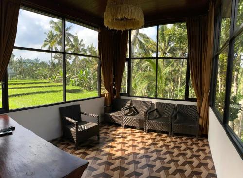 a room with chairs and large windows and a table at Kampoeng Joglo Ijen in Banyuwangi