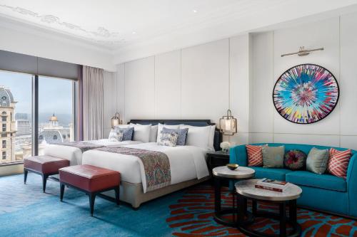 a hotel room with a bed and a blue couch at Grand Lisboa Palace Macau in Macau
