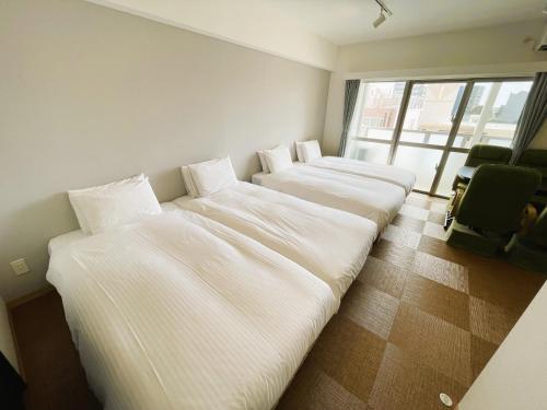 una fila di letti in una stanza con finestra di BiBi Hotel Cosmos Shintoshin a Naha