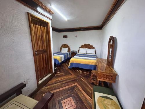 a room with two beds and a wooden floor at Hotel Colonial Taxco in Taxco de Alarcón