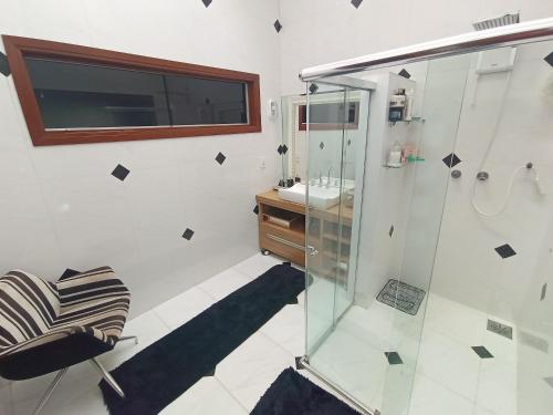 フォス・ド・イグアスにあるCasa Central Art Decor com Piscina e BBQのバスルーム(ガラス張りのシャワー、シンク付)