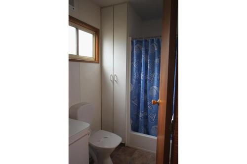 a bathroom with a toilet and a blue shower curtain at Southside Village in Fyshwick