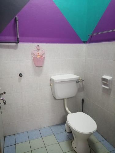 ein Bad mit einem WC und einer farbenfrohen Decke in der Unterkunft Iman Guesthouse in Jitra