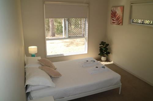 1 dormitorio con cama con almohadas y ventana en Honeybee Wellness Resort, en Kandanga