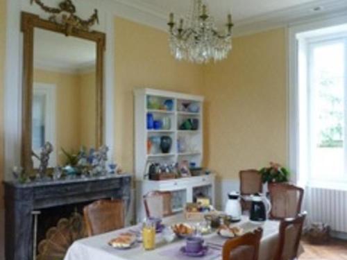 une salle à manger avec une table et un miroir dans l'établissement Château XIXe avec parc, chambres spacieuses et petit déjeuner local, proche forêt et cité médiévale - FR-1-410-411, à Parennes