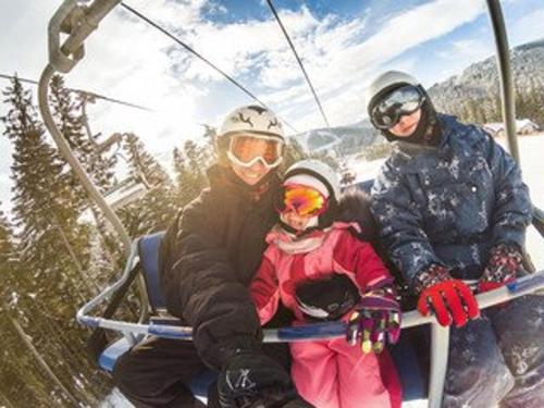 un groupe de personnes assises sur une remontée mécanique dans l'établissement Charmant 2 pièces avec balcon et parking - Proche centre et pistes - 4 pers. - FR-1-595-86, à Notre-Dame-de-Bellecombe