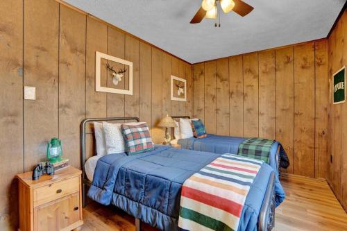 two beds in a room with wood paneled walls at Serene & Fun Family Gem ~ Big Bass Lake Community! in Gouldsboro