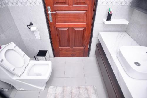 La salle de bains est pourvue de toilettes, d'un lavabo et d'une porte. dans l'établissement PearlCrest townhomes, à Kampala