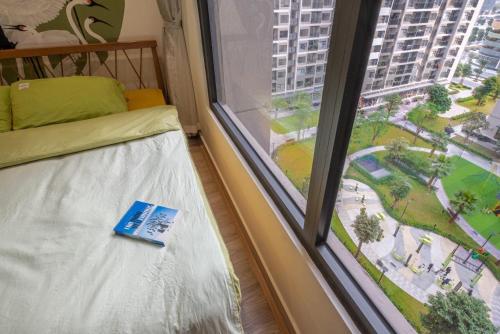 ein Buch auf einem Bett neben einem Fenster in der Unterkunft Căn Home đẹp in Hanoi