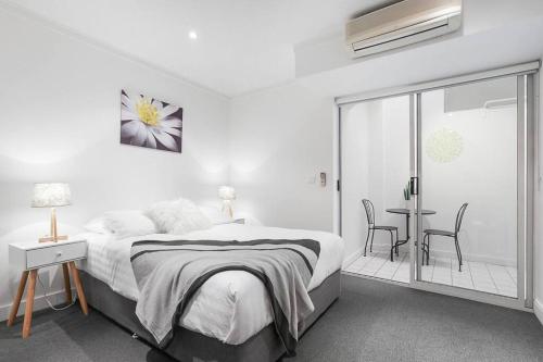 biała sypialnia z łóżkiem, stołem i krzesłami w obiekcie Backpacker's Delight on Lygon Street near RMIT w Melbourne