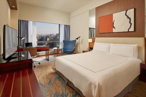 崑山市にあるParadox Kunshanのベッド、デスク、テレビが備わるホテルルームです。