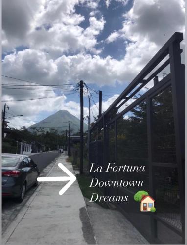 a sign on the side of a road with a car at La Fortuna Donwtown Dreams in Fortuna