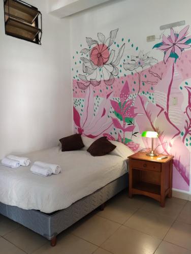 - une chambre avec un lit orné d'une fresque murale représentant des fleurs dans l'établissement Hospedajes JUJUY, à Palpalá