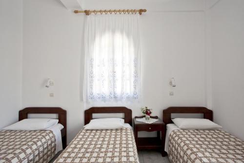 two beds in a room with a window at Ancient Thera Studios in Perissa