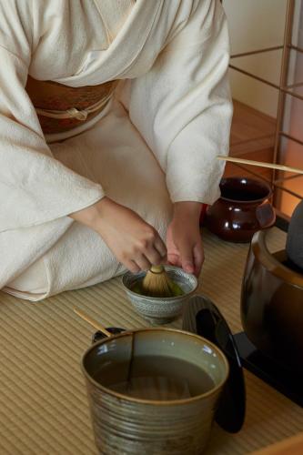 a woman in a towel is stirring a bowl of food at Dusit Thani Kyoto in Kyoto