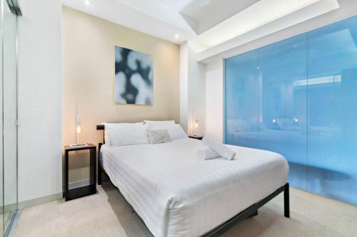 um quarto com uma cama branca e uma parede de vidro em Flinders Escape - Explore the Best of Melbourne em Melbourne