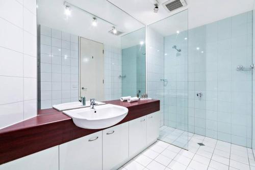 uma casa de banho branca com um lavatório e um espelho em Flinders Escape - Explore the Best of Melbourne em Melbourne