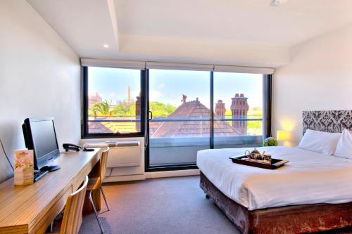 a bedroom with a bed and a desk and a window at Seasons Heritage Melbourne in Melbourne