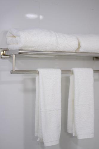 a towel rack with white towels on it in a bathroom at Semporna Garden Hotel in Semporna