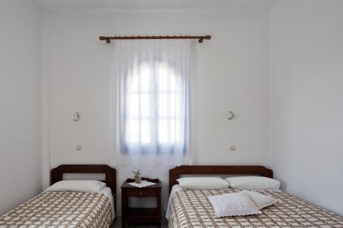two beds in a white room with a window at Ancient Thera Studios in Perissa