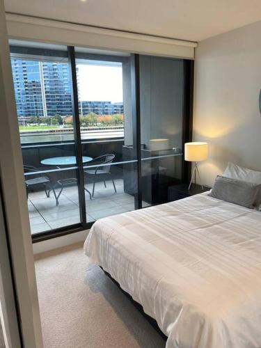 a bedroom with a bed and a balcony with a table at Wyndel Apartments MEL81306s in Melbourne