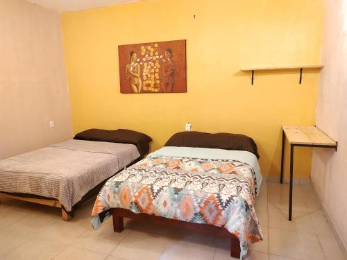 2 łóżka w pokoju z żółtymi ścianami w obiekcie Casa Corazon w mieście Oaxaca