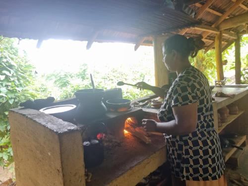 a woman standing in front of a stove at Silver Hill Ecovillage in Kurunegala