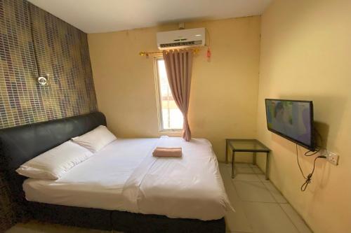 a bedroom with a bed and a window and a television at OYO 92932 Guesthouse Marbella in Nongsa