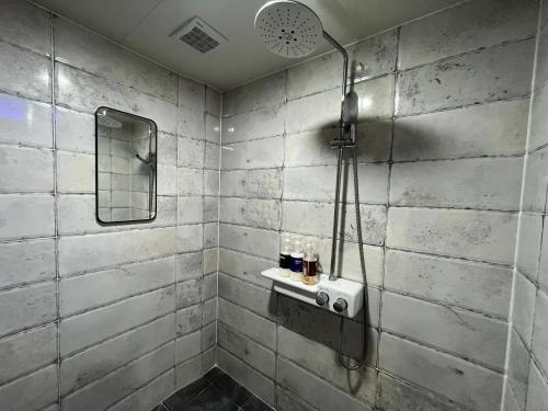 a bathroom with a shower and a mirror at Maldives Hotel & Hostel in Busan